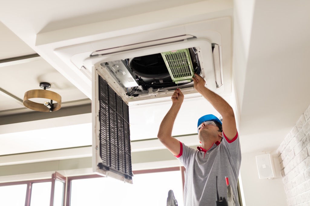 Heat pump vs air conditioner - man installs air conditioner in room