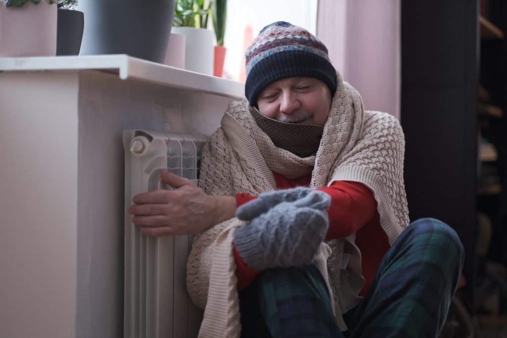 Man shivers by radiator